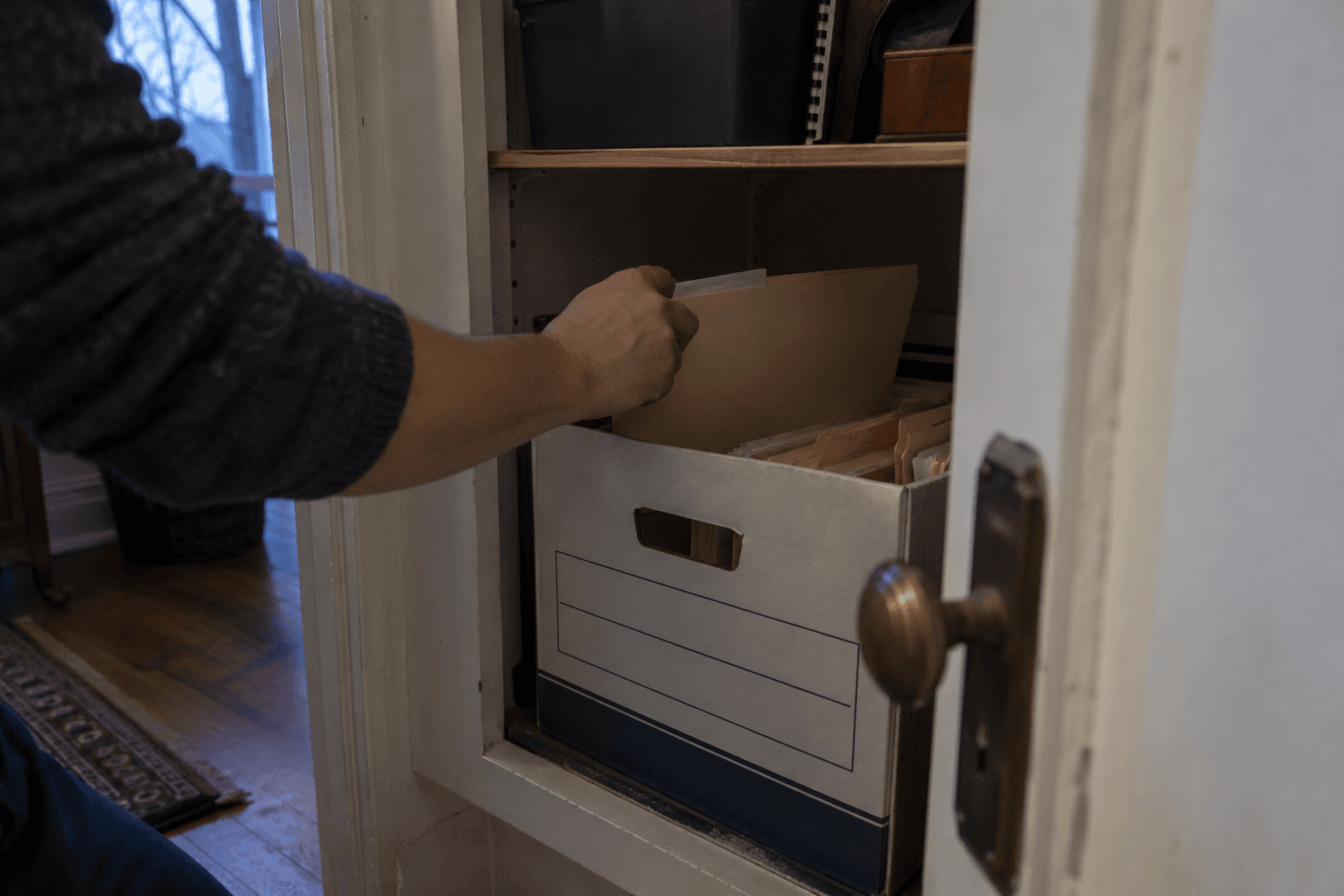 A folder being put into an archive box in a cupboard.