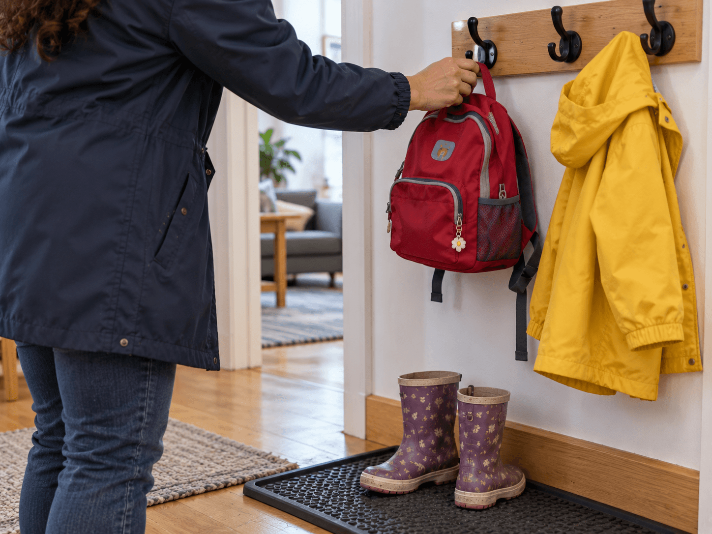 Sonia hangs her daughter's backpack beside the raincoat and boots at home.