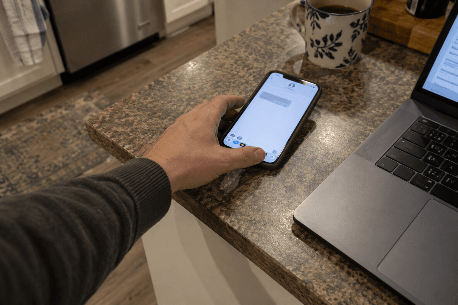 A phone with a message beside an open laptop.