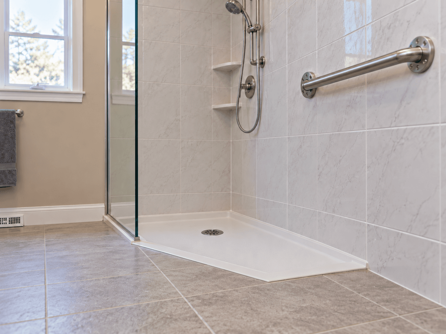 The completed shower has a low threshold and a fixed grab bar on its tiled wall.