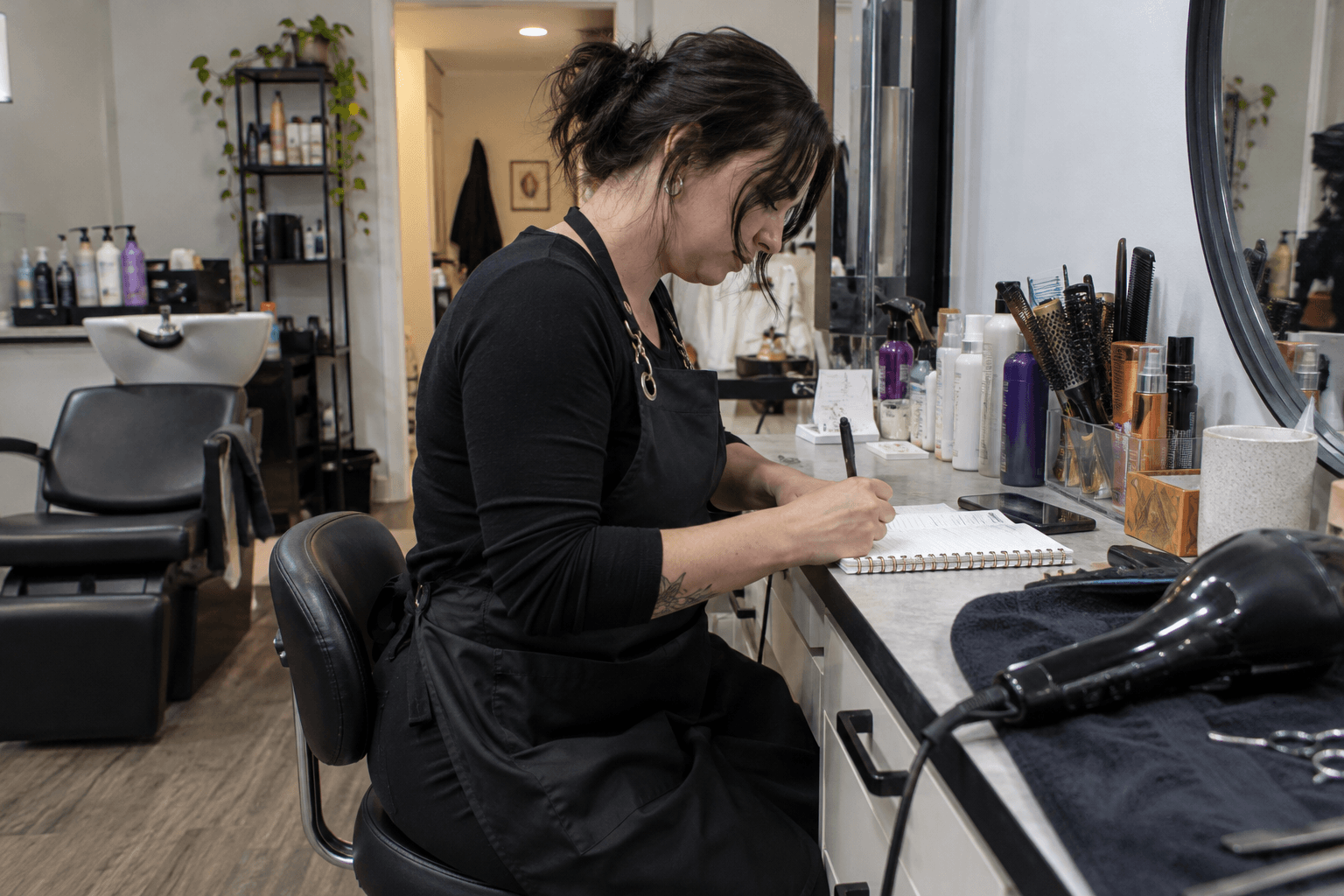 A hairdresser writing an invoice at a salon counter.