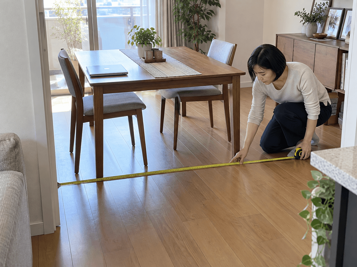 Maya measuring the floor area of the dining room she also uses for work.