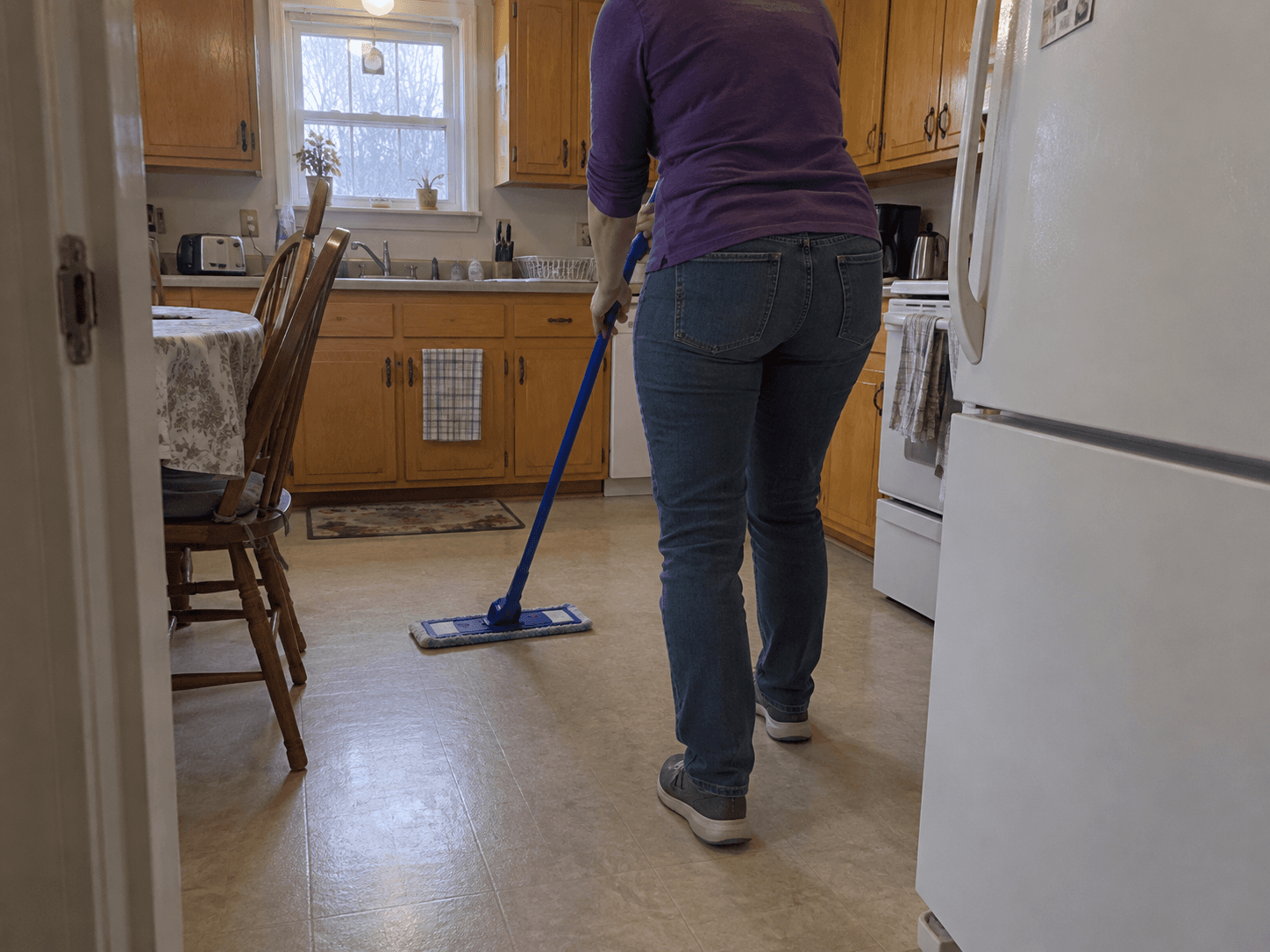 Une aide ménagère lave le plancher de la cuisine dans un bungalow.